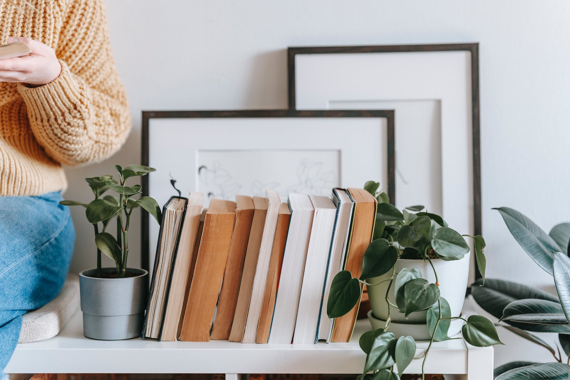 crop woman sitting near books and plant