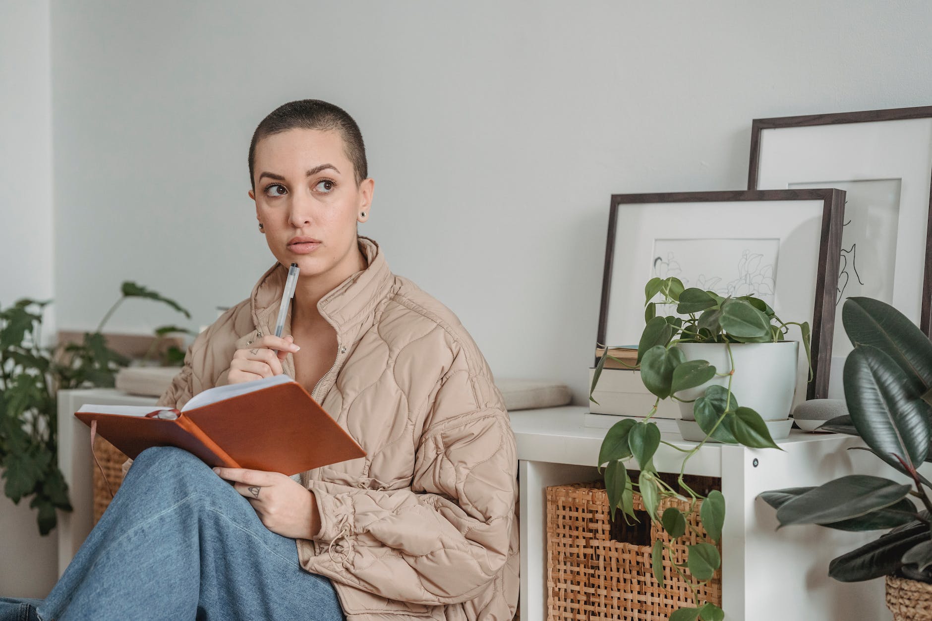 pensive woman in brown bubble jacket holding a notebook