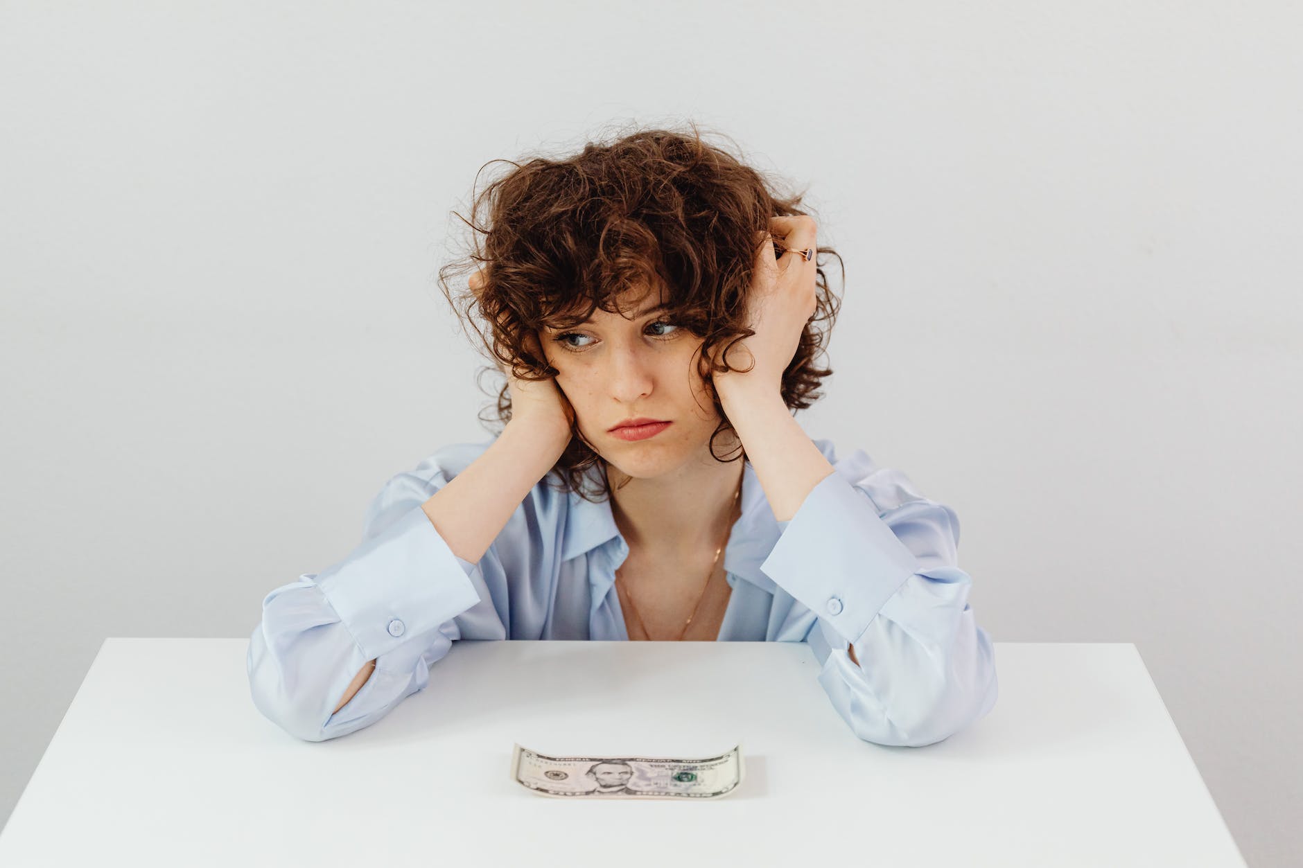 woman in blue long sleeve blouse near the money on table