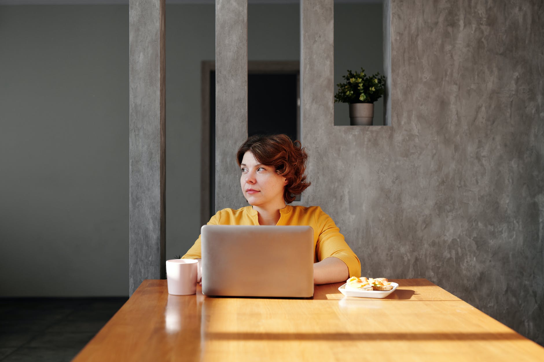 photo of woman sitting by the table while looking away