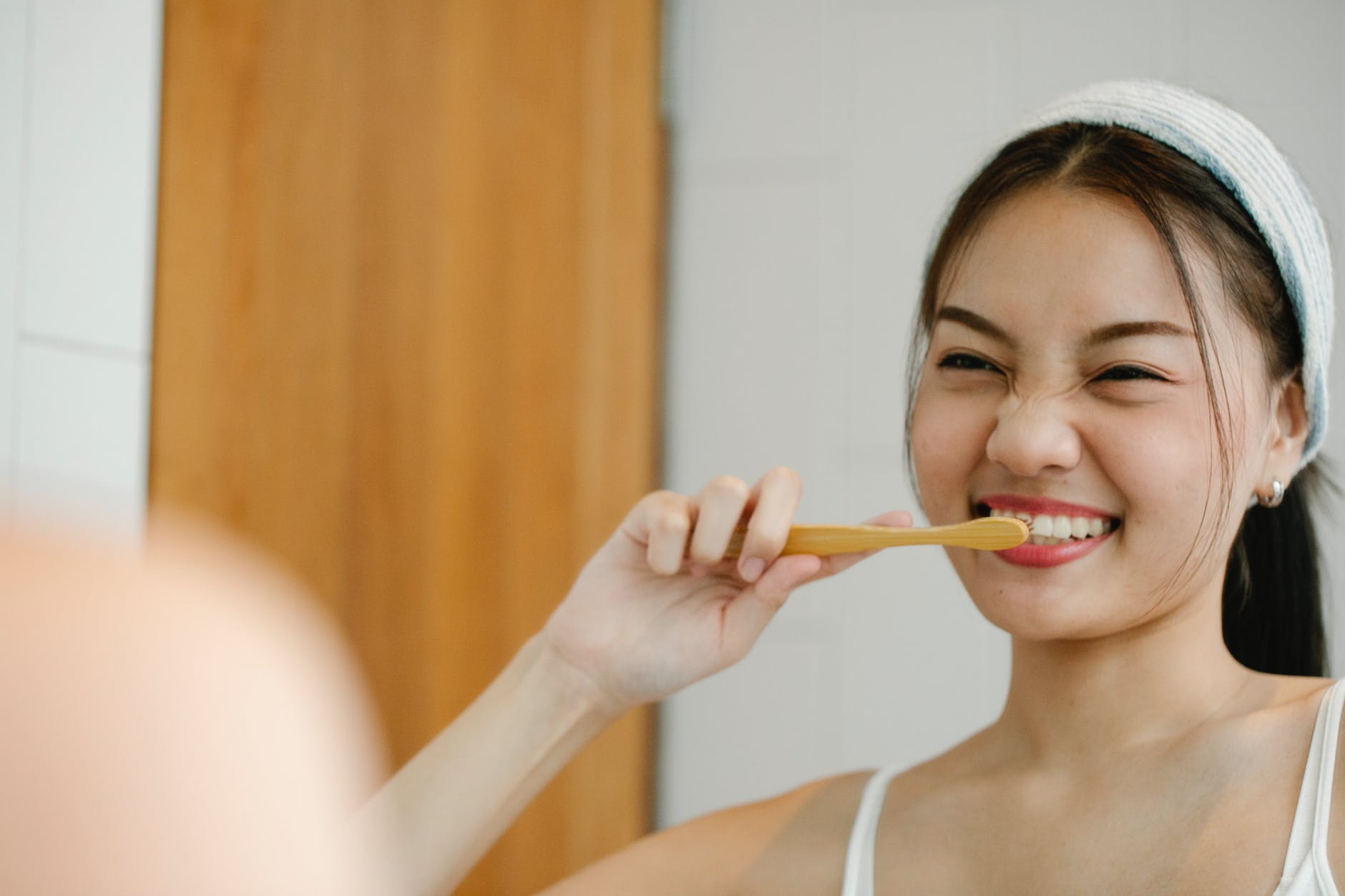positive asian woman brushing teeth