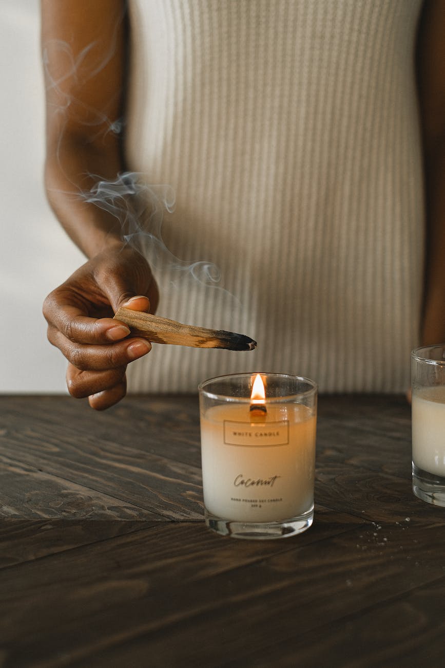 crop ethnic woman burning wooden stick at home