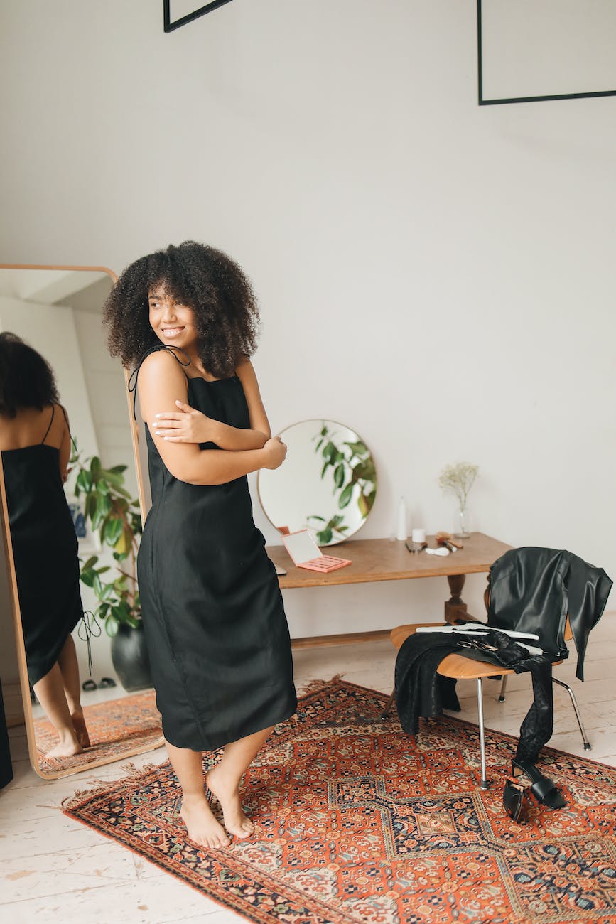 woman in black sleeveless dress standing beside brown wooden table