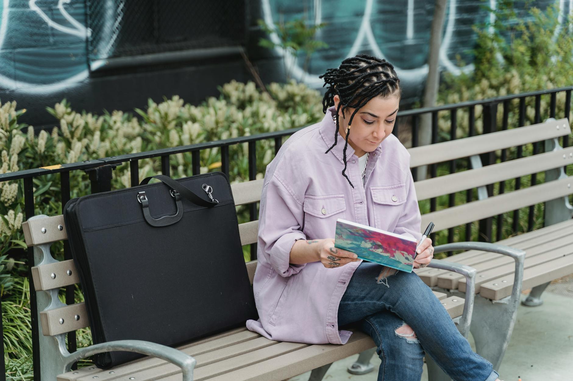 focused ethnic woman drawing on bench