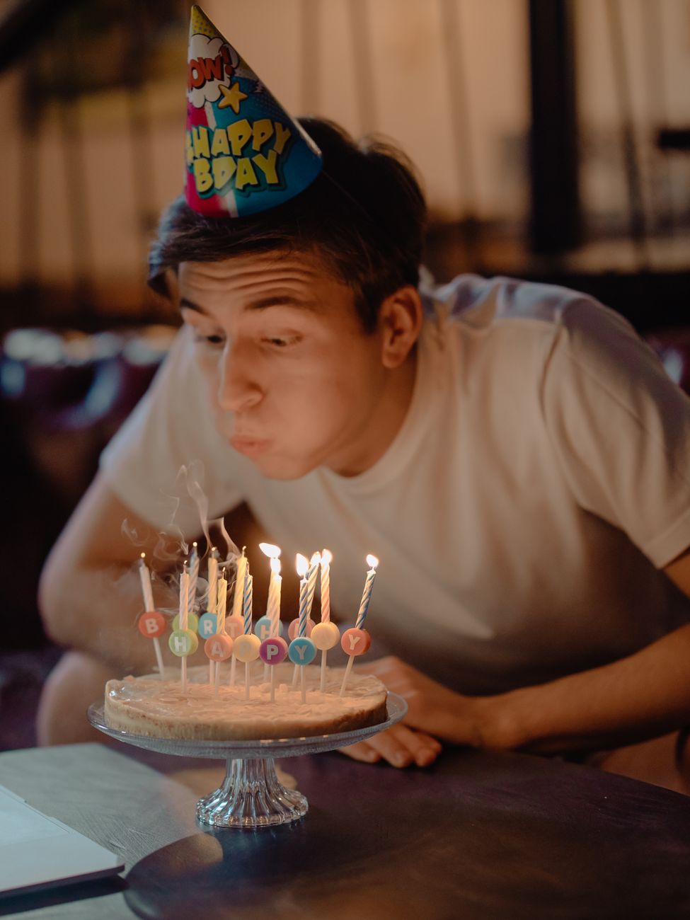 boy in white crew neck t shirt blowing candles on cake