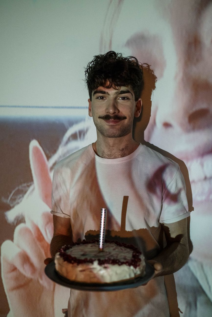 man in white t shirt holding a cake