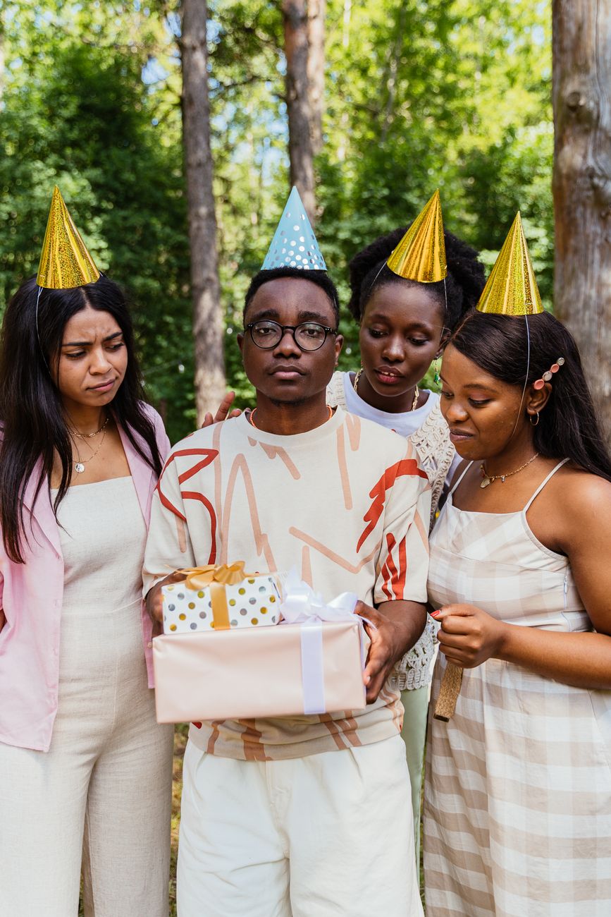 man surrounded by friends holding birthday gifts