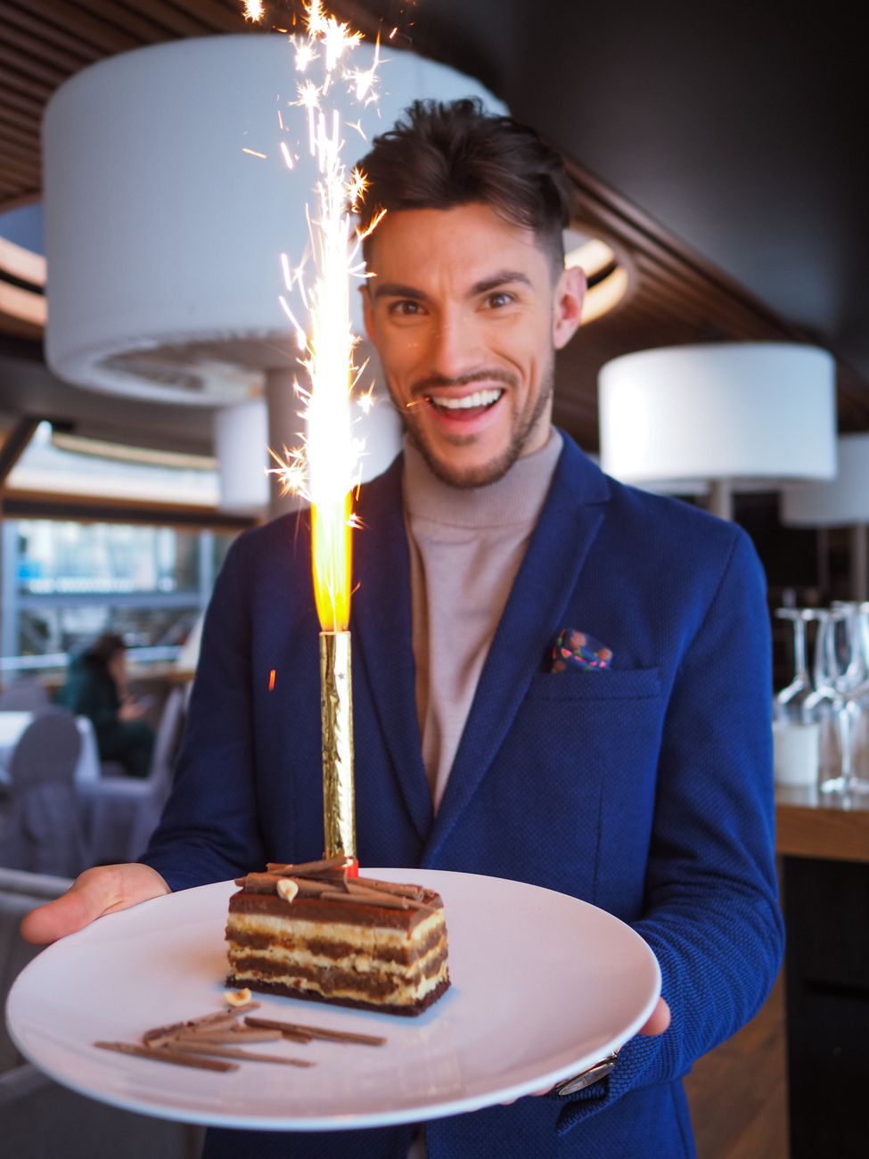 man in suit holding piece of cake with burning candle