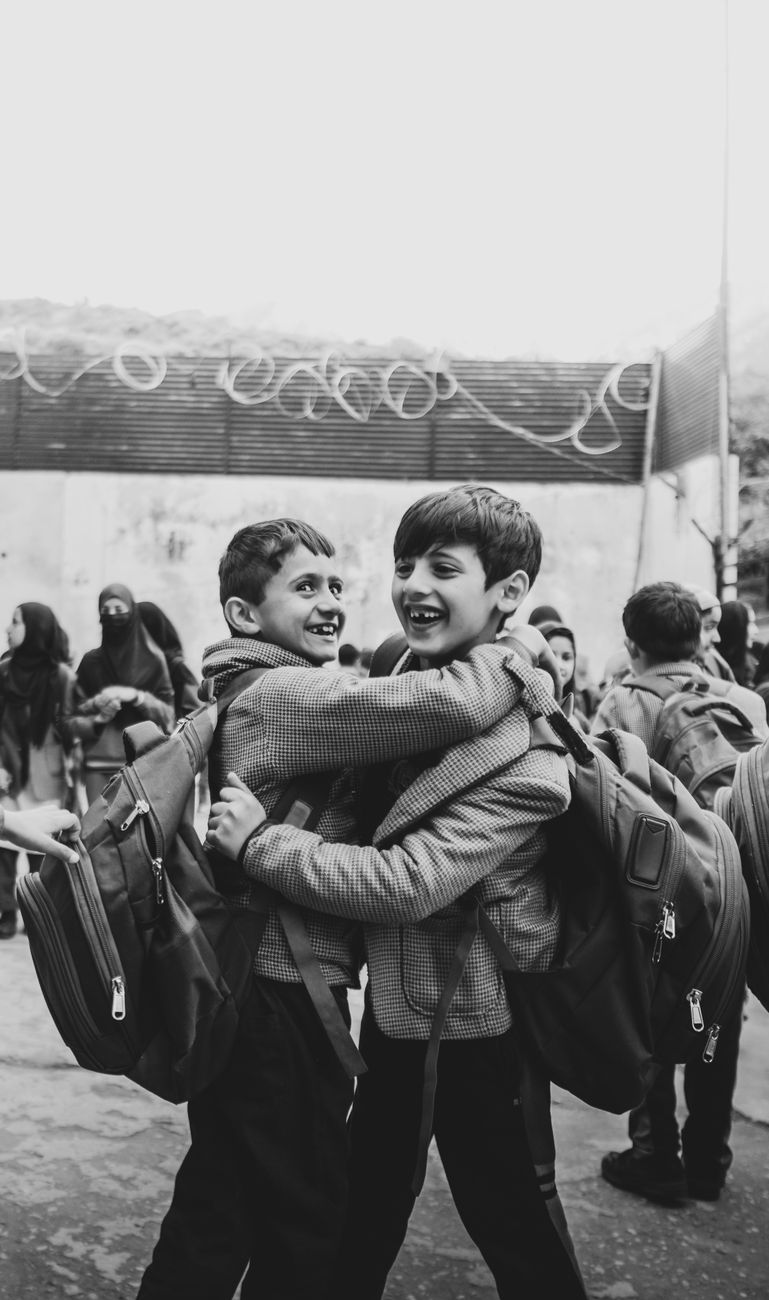 two boys hugging each other in a black and white photo