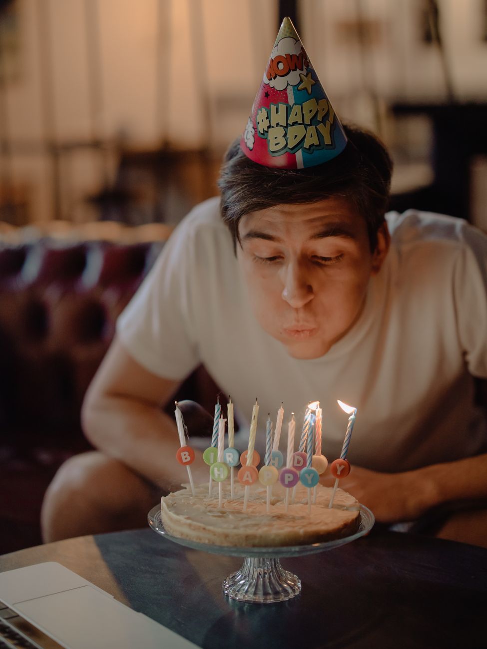 woman in white crew neck t shirt sitting in front of cake with candles
