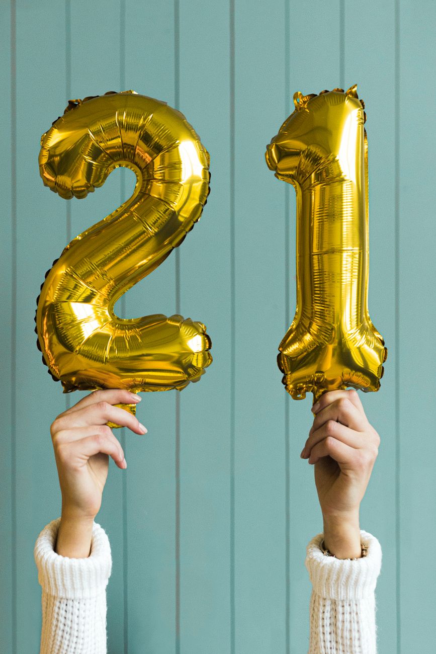 a person holding gold number balloons