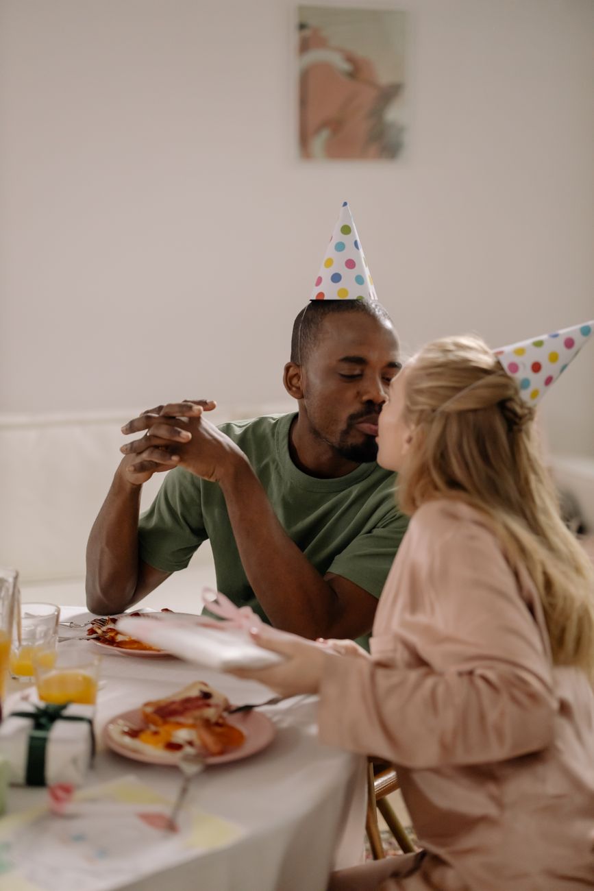 a couple wearing party hats while kissing each other