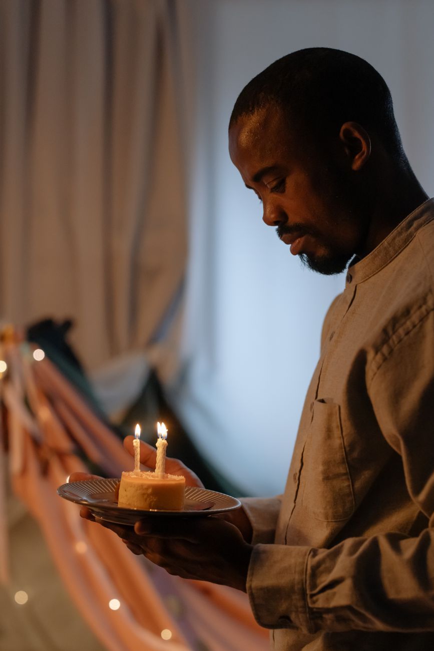 selective focus photo of a man in a gray shirt holding a plate with a birthday cake
