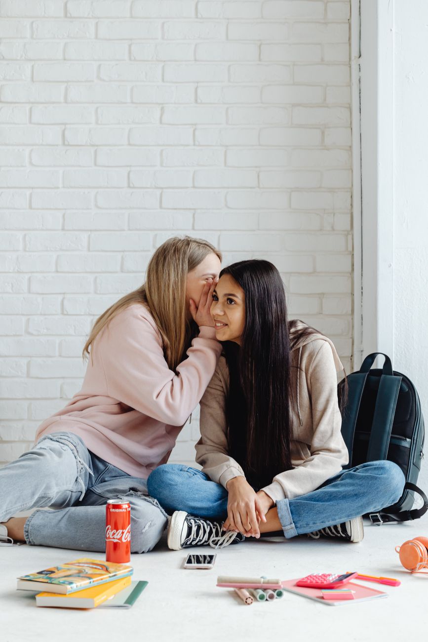 young women sitting on the floor while having a conversation
